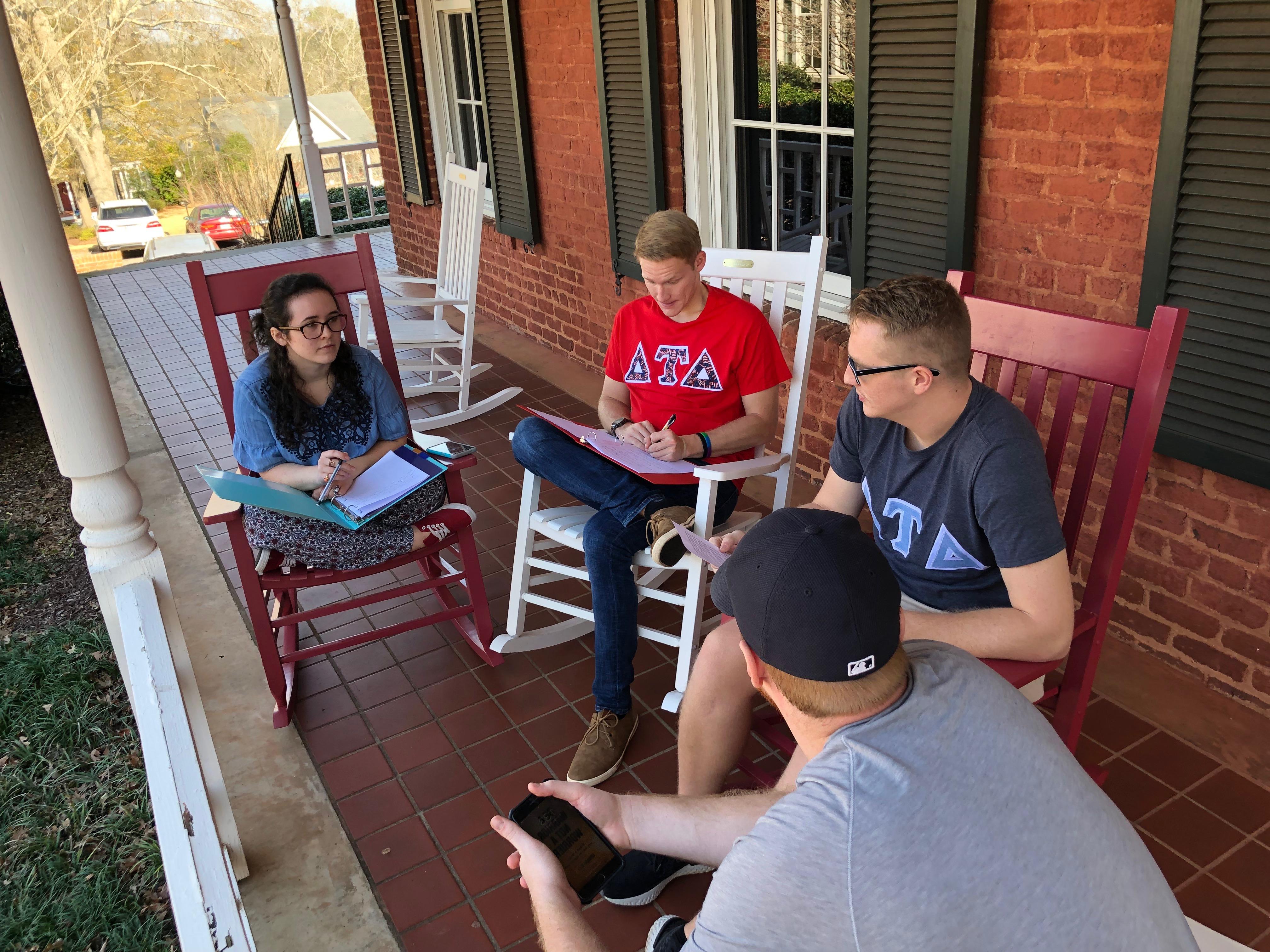 Three students sit on a swing at Smith Hall